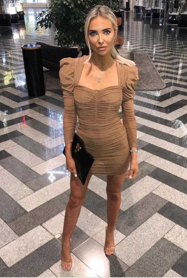 一袭优雅的碎花长裙衬托出她温婉的气质，在球场外的家庭日活动中，她正低头温柔地与孩子交谈，尽显母性光辉。