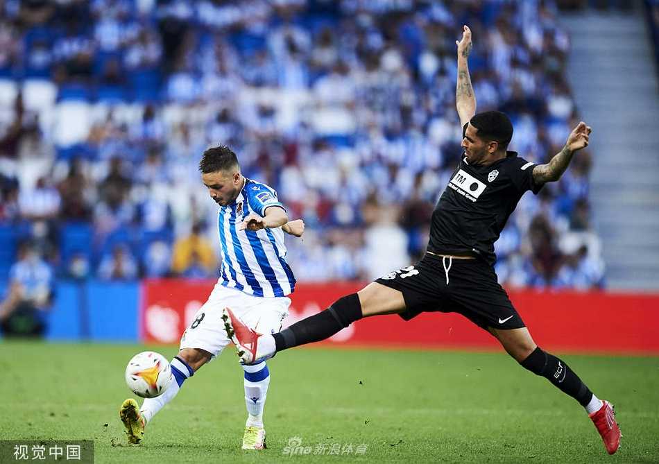 身穿蓝色战袍的皇家社会中场核心贾努扎伊在人群中巧妙控球，眼神犀利地寻找着足以撕裂对手防线的传球路线。