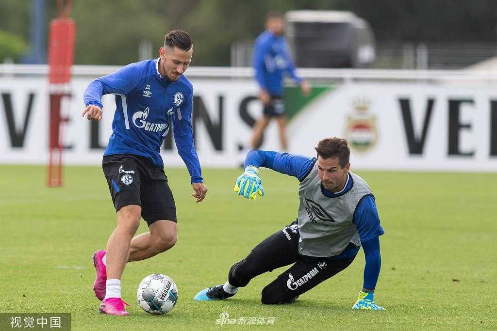 一位沙尔克球员独自在场边进行拉伸放松，他表情平静，目光望向远处的训练设施，似乎在为新赛季积蓄着最后的力量。