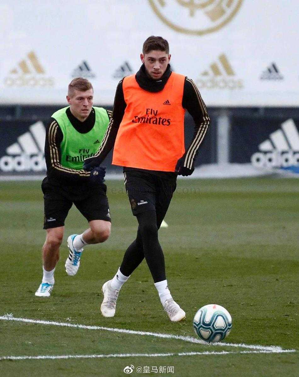 一名皇马球员正在单独进行带球绕杆练习，他脚下的皮球在标志盘间灵活穿梭，阳光将他的影子拉得很长，充满了训练的动感。