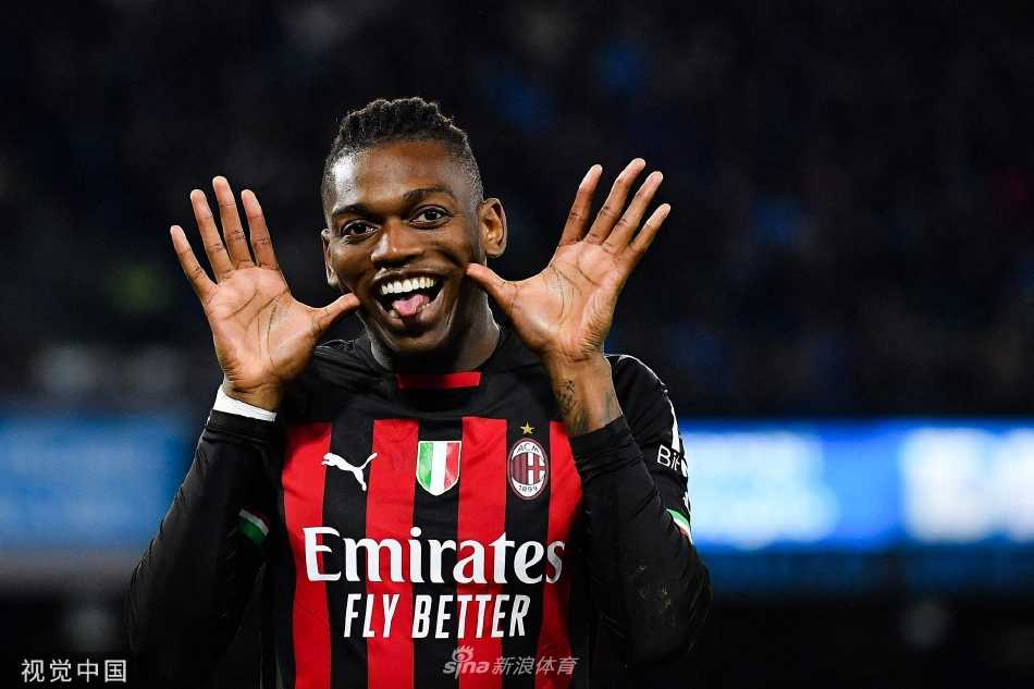 AC米兰前锋拉斐尔·莱奥在破门后张开双臂，面向客队看台激情庆祝，身后是目瞪口呆的那不勒斯后卫。