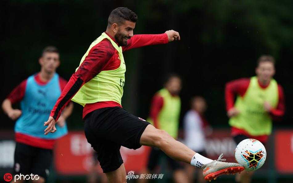 卡拉布里亚飞身铲截恰尔汗奥卢的传球，草屑在两人之间飞溅，身后看台的球迷横幅若隐若现，诠释着德比级别的对抗强度