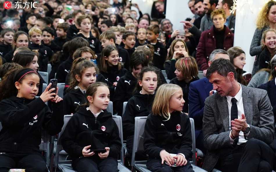 红黑军团的未来希望:AC米兰青年队的圣诞传承 几位身穿AC米兰训练服的年轻球员在装饰着彩带和铃铛的更衣室里互相拥抱,脸上洋溢着单纯而灿烂的笑容,背景里还能看到为队友准备的圣诞袜形状的小礼物。