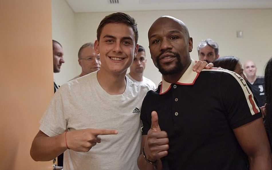 尤文图斯更衣室内一片欢腾，C罗赤裸着上身露出健硕的肌肉，与队友们围着意大利超级杯奖杯高歌，梅威瑟被邀请至人群中央，众人簇拥下两位传奇共同托起金杯，气氛热烈。