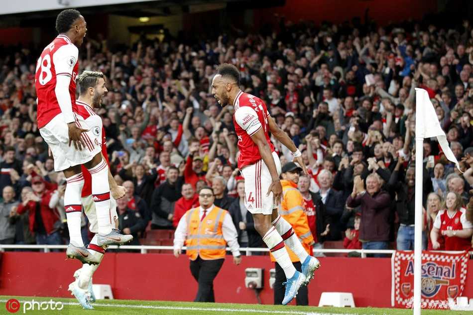 进球后的奥巴梅杨张开双臂激情滑跪，草屑飞溅，他张开的双臂仿佛要拥抱整个酋长球场的欢呼。