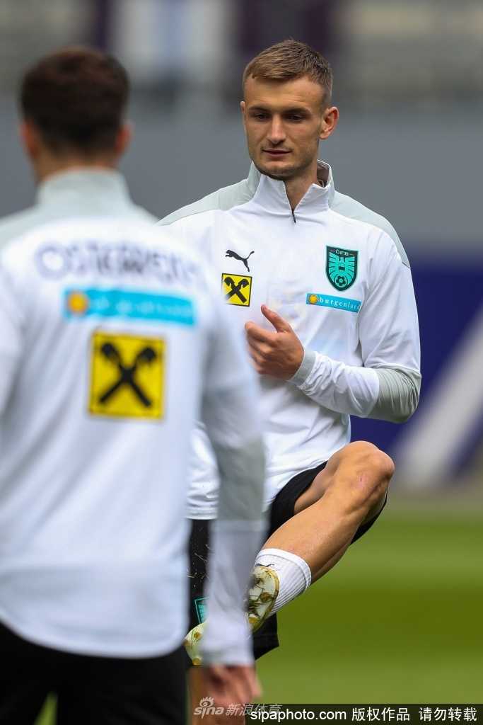 训练间隙，几名奥地利队员围在一起进行轻松的有球练习，他们脸上带着笑容，脚下却依然娴熟地摆弄着足球，展现了团队中既严谨又融洽的氛围。