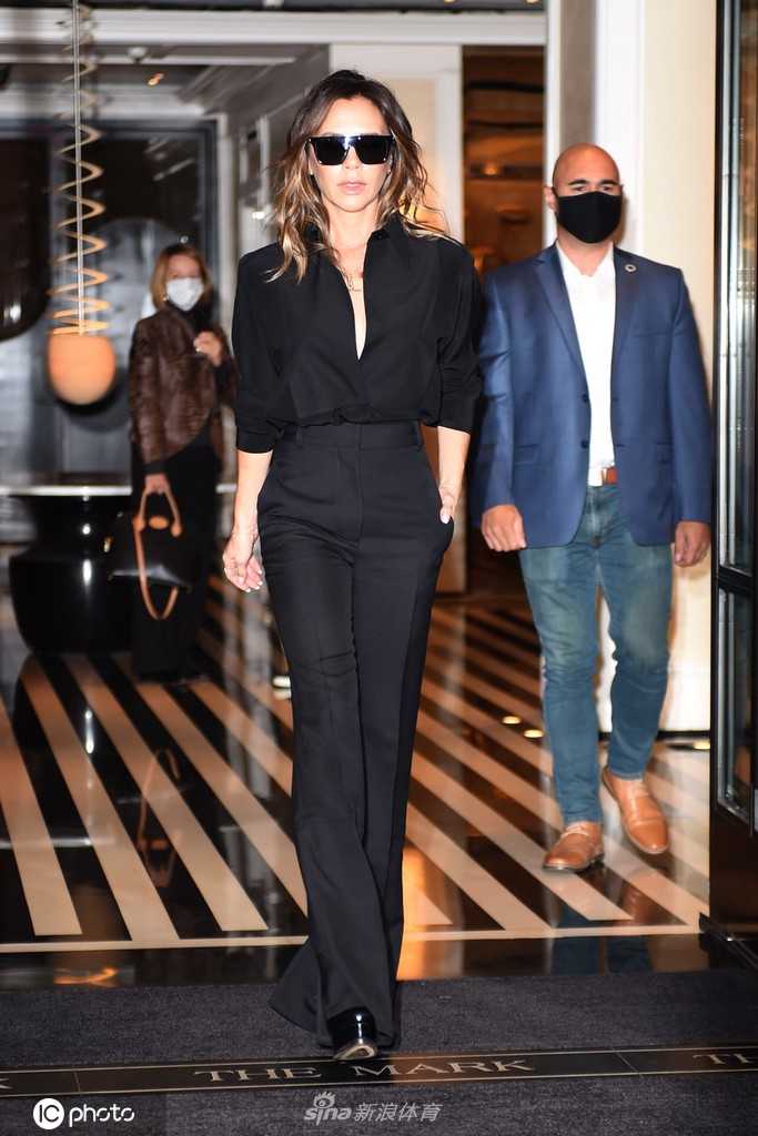 维多利亚驻足于街边，双手插兜的姿态显得格外放松且笃定。她的全黑造型在都市的柔和光线下泛着低调的光泽，虽然看不清墨镜后的眼神，但那种由内而外散发的自信与疏离感，依然是人们熟悉的那个‘时髦贝嫂’。