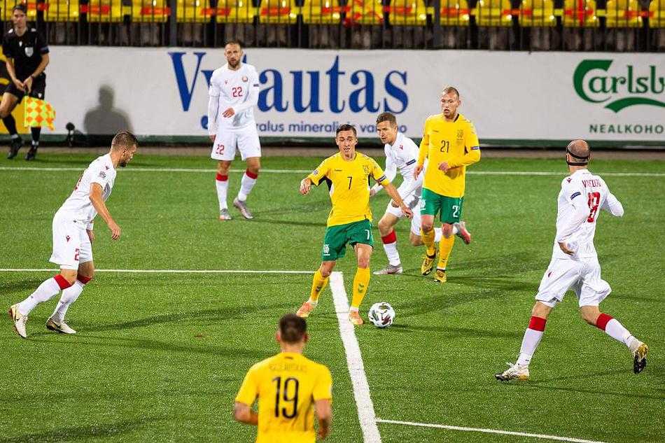 白俄罗斯球员萨奇夫科在角球混战中高高跃起头槌破门瞬间，皮球飞入网窝，他身后的立陶宛防守球员面露无奈，背景是湿漉漉的球场和模糊的看台。