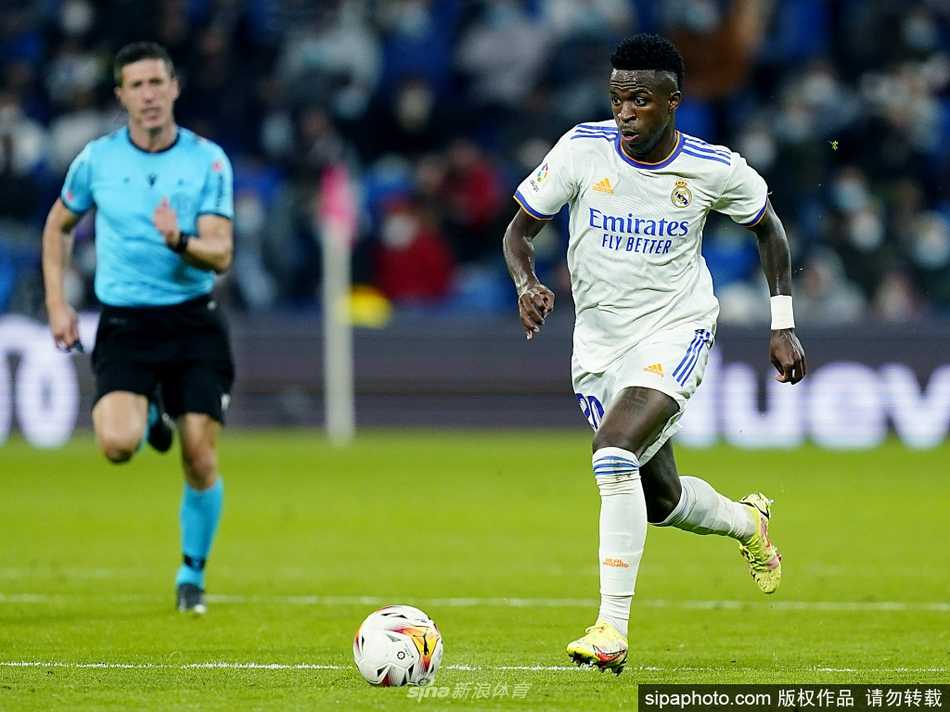 身披纯白战袍的维尼修斯在阳光下笑容灿烂，眼神中透露出对伯纳乌球场深深的眷恋与坚定，仿佛在向世界宣告这里就是他梦想的归宿。