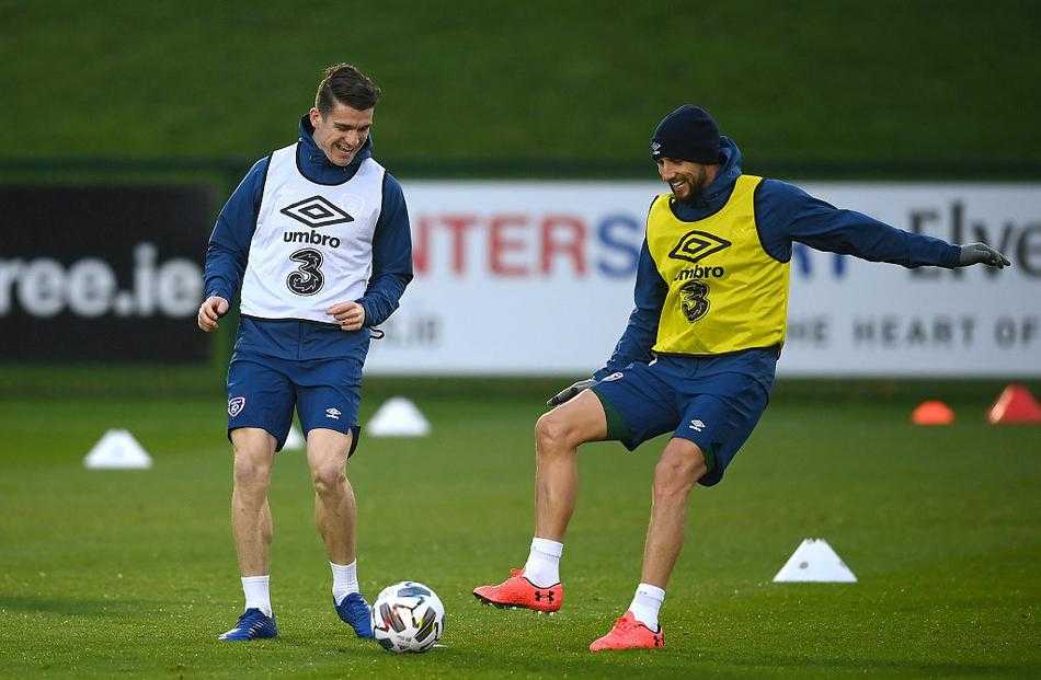 爱尔兰队球员们在训练场上进行分组对抗，一名中场球员正用外脚背送出一记精妙传球，阳光在他身后勾勒出健硕的轮廓，草坪上水珠飞溅，充满了力量与动感。