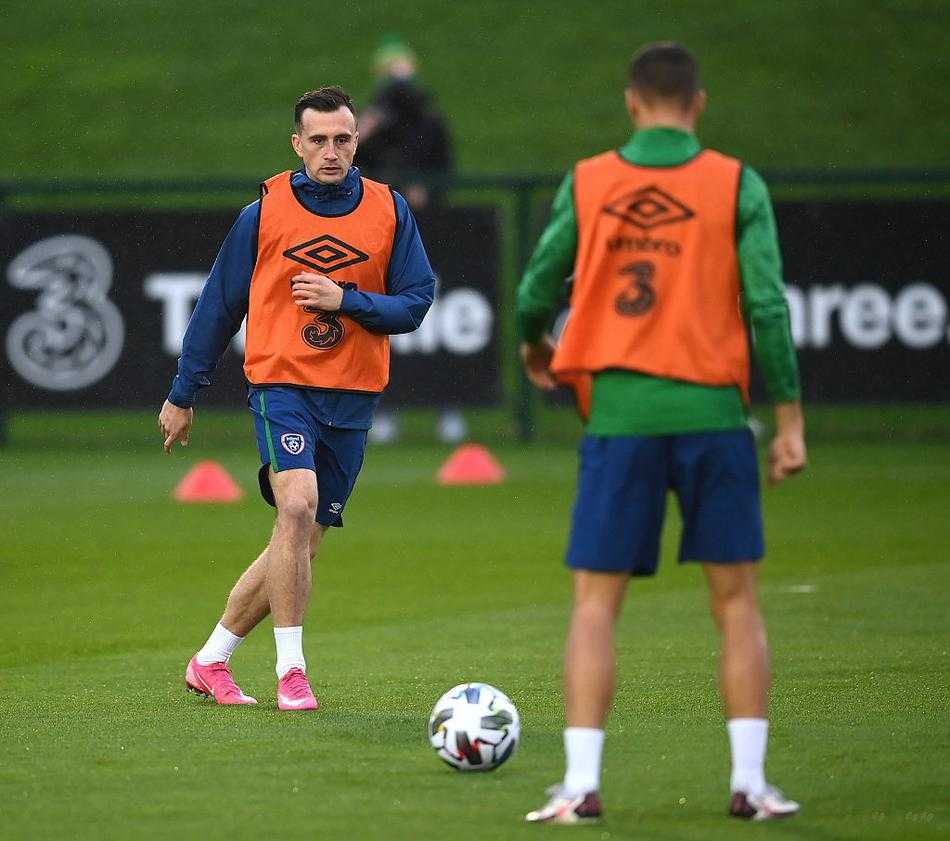 一名前锋球员在训练结束后独自加练射门，他面对空门冷静推射，皮球应声入网。远处的教练组成员正在收拾训练器材，晚霞将他的身影拉得很长，无声诉说着成功背后的汗水与坚持。