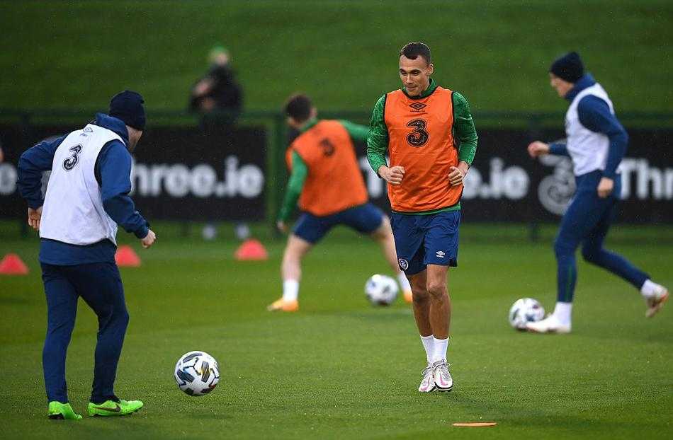 门将位置正在进行专项训练，守门员如猎豹般纵身侧扑，指尖几乎触碰到飞向死角的皮球。球网因扑救力量而剧烈晃动，身后是空旷的看台和阴沉的天空，凸显出训练的核心与专注。