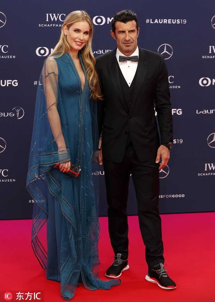 菲戈将手轻轻放在妻子的腰间，这个细微的动作充满了保护欲。海伦身着一袭设计感十足的黑色长裙，修身的剪裁将她高挑的身材展现得淋漓尽致，裙摆处若隐若现的薄纱更添几分浪漫，两人在镜头前留下的不仅是影像，更是岁月沉淀下的深情。