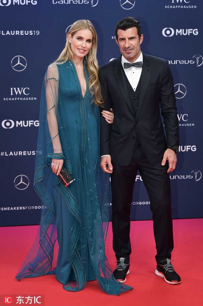 红毯上的菲戈侧身凝视着镜头，轮廓分明的侧脸线条宛如雕塑。身旁的海伦轻抚秀发，流苏耳饰在灯光下摇曳生姿，她微微一笑，那份从容与淡定，是岁月赋予这位超模最珍贵的礼物，也让人们看到了这对夫妻间的默契与和谐。