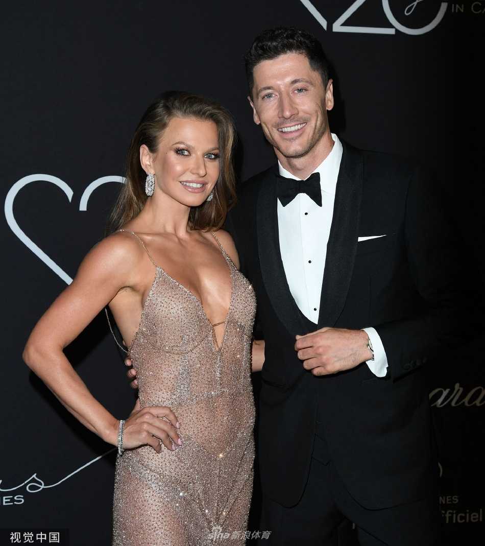 莱万温柔亲吻妻子安娜的脸颊，安娜手中拿着手机似在拍摄，记录下这甜蜜一刻，展现了他们生活中轻松有趣的互动。