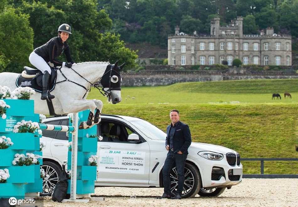 拍摄间隙，欧文放松地倚靠在围栏旁，与身边的马术界同仁轻松交谈，午后的阳光洒在他身上，氛围亲切而自然。