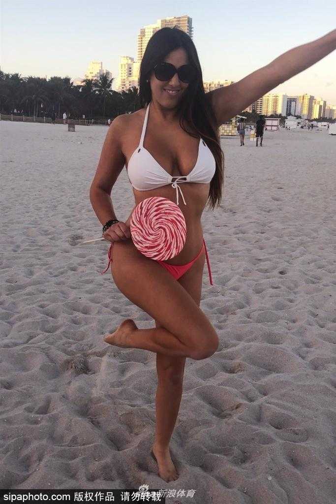 克劳迪娅·罗马尼在迈阿密海滩的阳光下，身穿亮黄色比基尼，回眸一笑，金色的阳光洒在她古铜色的肌肤上，展现出健康又迷人的魅力。