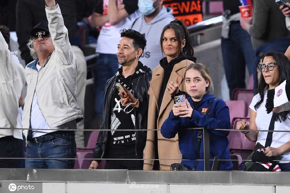 她专注地望向绿茵场，双手轻轻交握，仿佛正在为场上的每一次拼搏暗自加油，神情认真而动人。