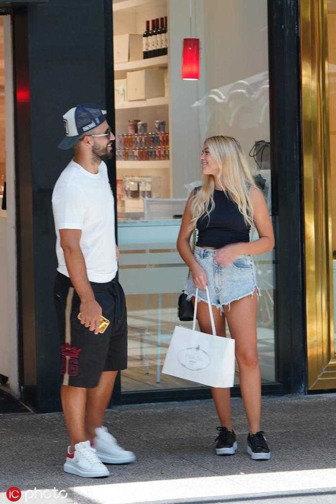 阿奎罗和女友索菲亚在店内流连忘返，索菲亚正在试戴一副太阳镜，而阿奎罗则在一旁静静欣赏，画面充满了生活气息与甜蜜的互动。