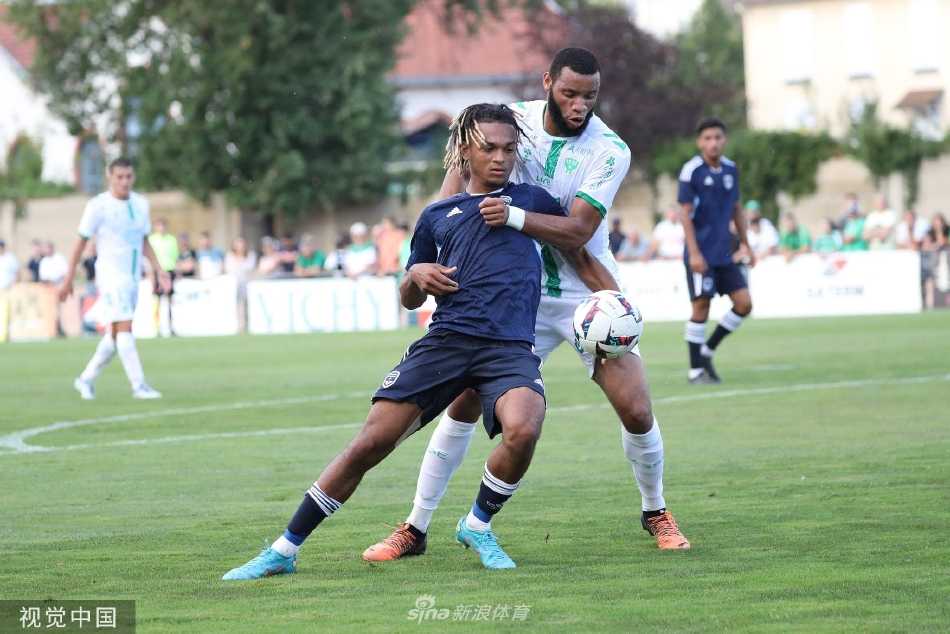 圣埃蒂安前锋带球突破波尔多后卫的严密防守，双方在绿茵场上展开速度与力量的博弈