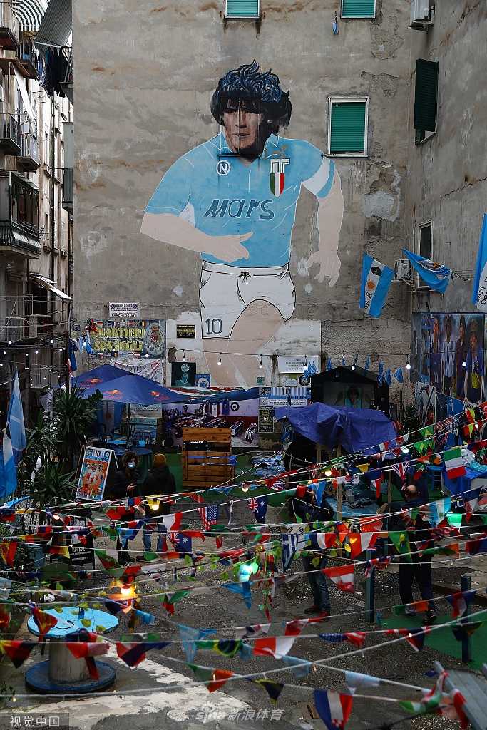 一名小球迷身穿经典的马拉多纳10号那不勒斯球衣，双手指天，稚嫩的脸庞上写满了对传奇的景仰，象征着足球精神的代代相传。