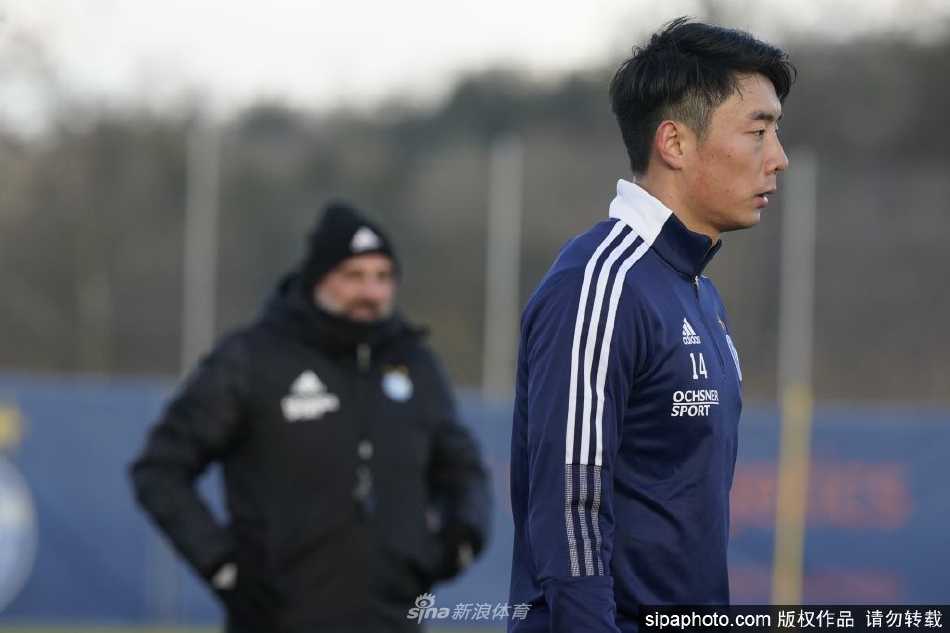 李磊身披草蜢队4号战袍在赛场边凝神思考，侧影透出坚韧气质