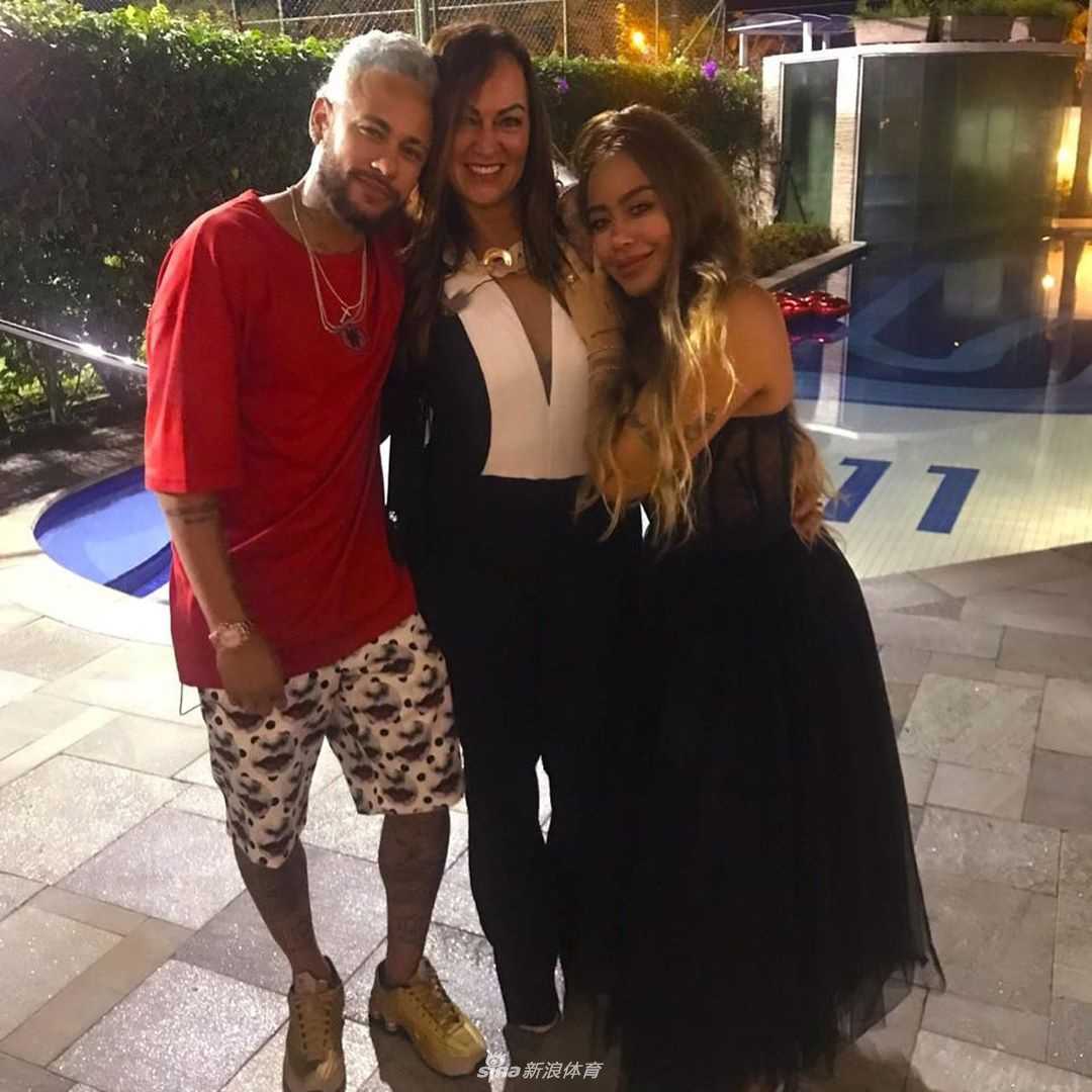 法国球星姆巴佩身着一件印有卡通麋鹿图案的红色毛衣，手捧礼物盒，脸上露出邻家大男孩般阳光灿烂的笑容